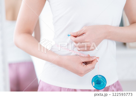 メジャーを手にするダイエット中の女性　顔無し 122593773