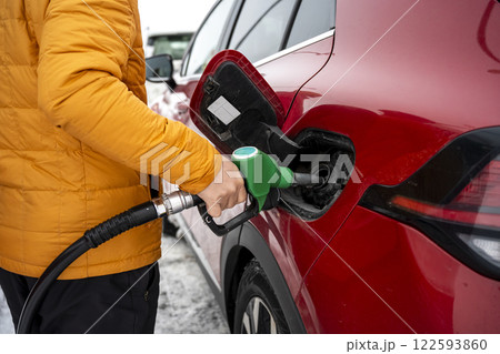 Man refueling car at a gas station in Iceland. Transportation, travel, industry, service, winter background, or wallpaper Man refueling car at a gas station in Iceland. Transportation, travel, industry, service, winter background, or wallpaper 122593860
