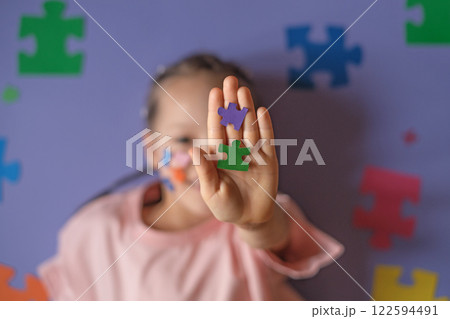 Colored puzzles in a child's hand close-up on a purple background.  A concept on education and autism. 122594491