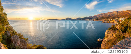 Coastal view of Becici and Budva from a rocky cliff, bathed in golden sunset light with the sea stretching toward the horizon. Coastal view of Becici and Budva from a rocky cliff, bathed in golden sunset light with the sea stretching toward the horizon. 122595106