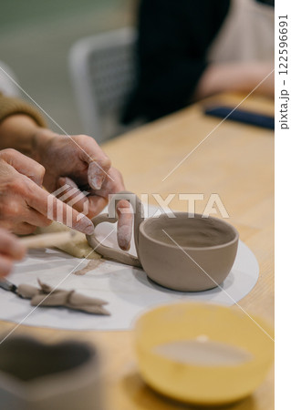 Pottery student modeling clay mug, learning traditional sculpting techniques. Pottery student learns sculpting techniques, modeling a unique handmade cup Pottery student modeling clay mug, learning traditional sculpting techniques. Pottery student learns sculpting techniques, modeling a unique handmade cup 122596691