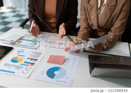 Business team analyzing documents, graphs, and data with a laptop, tablet, and smartphone. Collaboration, strategy, and success in a modern office. 122598916