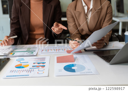 Business team analyzing documents, graphs, and data with a laptop, tablet, and smartphone. Collaboration, strategy, and success in a modern office. 122598917