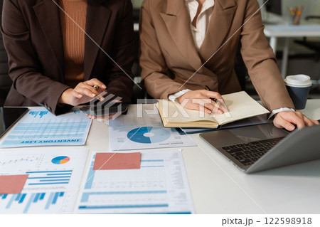 Business team analyzing documents, graphs, and data with a laptop, tablet, and smartphone. Collaboration, strategy, and success in a modern office. 122598918