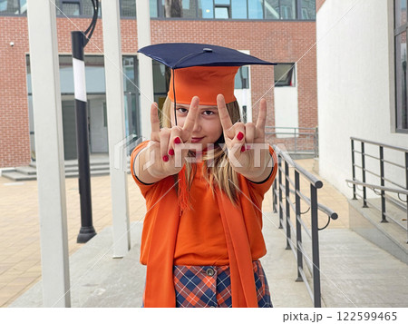 A young girl in a graduation cap smiling and looking at camera. Education and graduation concept A young girl in a graduation cap smiling and looking at camera. Education and graduation concept 122599465