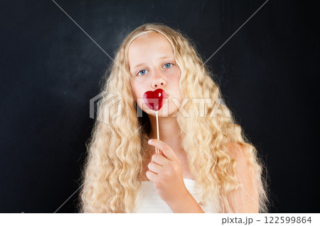 Pretty young child girl with blond hair and blue eyes holding red heart Pretty young child girl with blond hair and blue eyes holding red heart 122599864