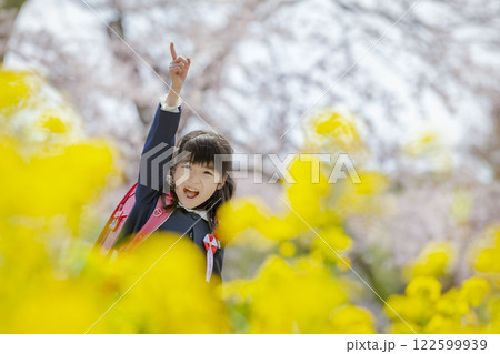 菜の花と桜の咲く公園を歩く小学一年生 122599939