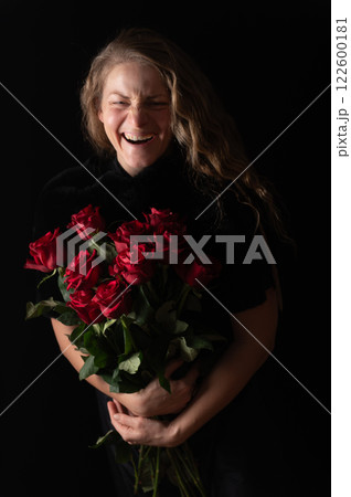 Beautiful young woman with bouquet of red roses flowers on black studio background Beautiful young woman with bouquet of red roses flowers on black studio background 122600181