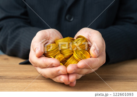 Businessman holding a handful of gold coins. Wealth and capital. High salary. Income and bonuses. High margin. Businessman holding a handful of gold coins. Wealth and capital. High salary. Income and bonuses. High margin. 122601093