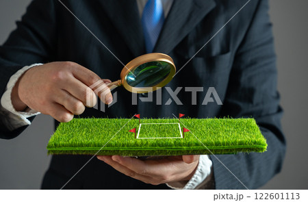 A businessman examines a plot of land with a magnifying glass. Purchase and sale of land. Plot valuation. Checking for arrests and possible risks to the successful conclusion of the contract. A businessman examines a plot of land with a magnifying glass. Purchase and sale of land. Plot valuation. Checking for arrests and possible risks to the successful conclusion of the contract. 122601113