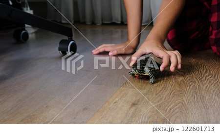 child gently pushes a small turtle on a skateboard across the wooden floor. The scene captures a creative and playful interaction between the child and their pet, emphasizing curiosity and imagination child gently pushes a small turtle on a skateboard across the wooden floor. The scene captures a creative and playful interaction between the child and their pet, emphasizing curiosity and imagination 122601713