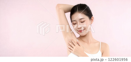Beautiful Korean woman with flawless underarm skin posing confidently in a soft pink background 122601956