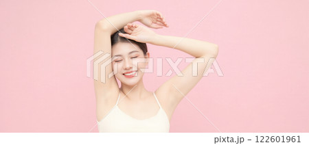 Beautiful Korean woman with flawless underarm skin posing confidently in a soft pink background 122601961