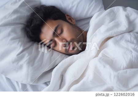 Indian tired young man lying sleeping in white bed, sound asleep at night 122602016