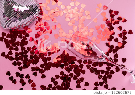 Minimalist disco heart Champagne Glass Filled spilling Red Glitter on Pink Backdrop 122602675