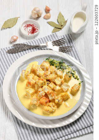 pollock cubes poached in cream saffron sauce pollock cubes poached in cream saffron sauce 122603729