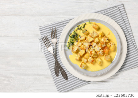 pollock cubes poached in cream saffron sauce pollock cubes poached in cream saffron sauce 122603730