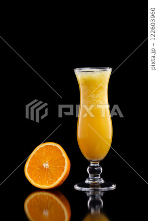 Closeup glass of fresh orange juice with ice isolated at black background. Closeup glass of fresh orange juice with ice isolated at black background. 122603960