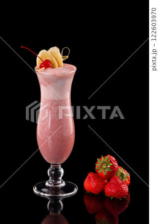 Glass of fresh strawberry milkshake decorated with cocktail cherry and banana slices isolated at black background. Glass of fresh strawberry milkshake decorated with cocktail cherry and banana slices isolated at black background. 122603970
