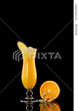 Closeup glass of fresh orange juice with ice decorated with ginger isolated at black background. 122603981