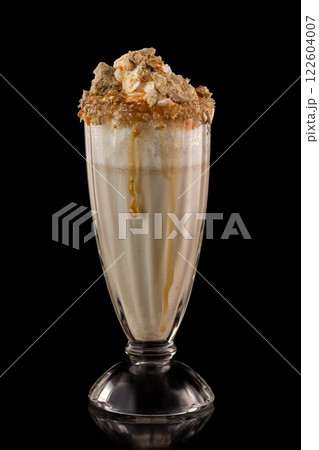 Glass of milkshake decorated with halva and caramel isolated at black background. 122604007