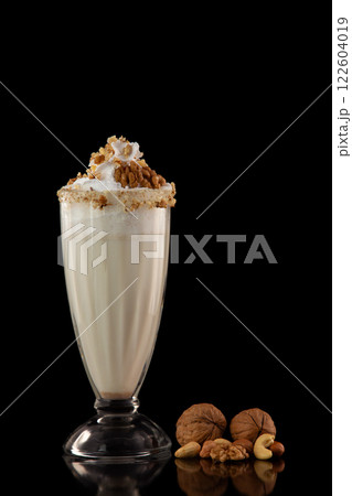 Glass of sweet milkshake with nuts isolated at black background. 122604019