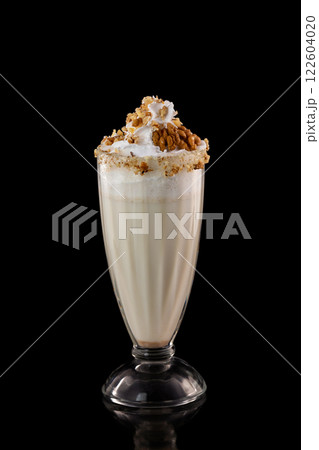 Glass of sweet milkshake with nuts isolated at black background. 122604020