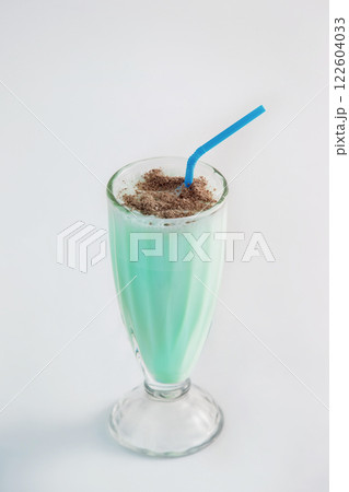 Fresh healthy green cocktail with cacao powder and blue straw in glass isolated at white background. Fresh healthy green cocktail with cacao powder and blue straw in glass isolated at white background. 122604033