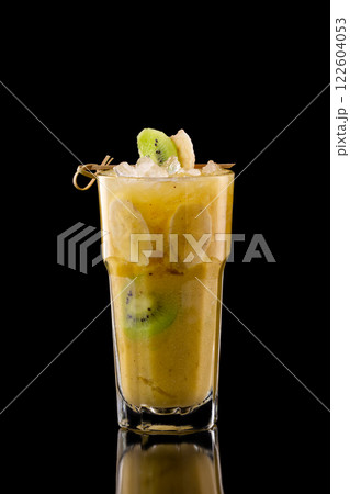 Closeup glass of fresh yellow banana fruit shake with kiwi isolated at black background. 122604053