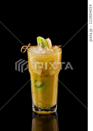Closeup glass of fresh yellow banana smoothie with kiwi isolated at black background. 122604054