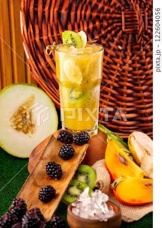 Verical glass of tropical healthy banana fruit cocktail at decorated with fruits and berries table background. 122604056