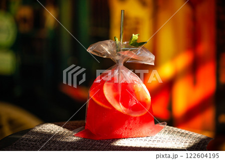 Red strawberry cocktail served in a plastic bag at colorful bar background. Red strawberry cocktail served in a plastic bag at colorful bar background. 122604195