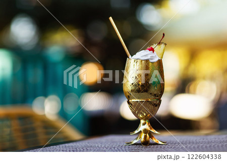 Closeup pina colada cocktail served in metal golden color glass looking like pineapple at bar background. 122604338