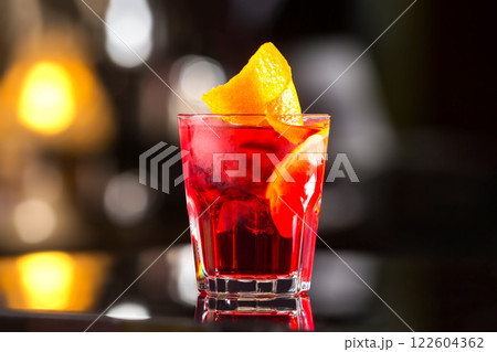 Closeup glass od red alcoholic cocktail decorated with lemon at bright bar stand background. 122604362