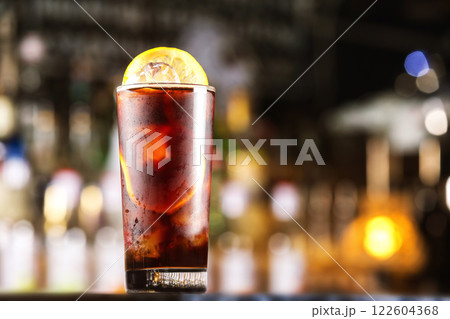 Rum cola cocktail with ice cubes and lemon at festive bar stand background. Rum cola cocktail with ice cubes and lemon at festive bar stand background. 122604368