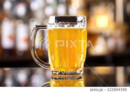 Closeup image of mug with golden cold light beer at bar background. Closeup image of mug with golden cold light beer at bar background. 122604390