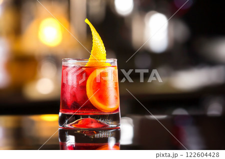 Closeup glass of negroni cocktail decorated with citrus at bar stand festive background. 122604428