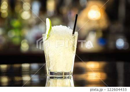Closeup glass of soda water decorated with lime slice and frappe at bar background. Closeup glass of soda water decorated with lime slice and frappe at bar background. 122604433