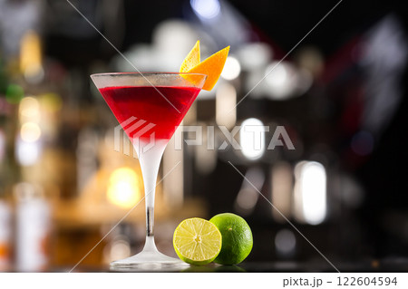 Closeup glass of cosmopolitan cocktail decorated with orange at bar background. Closeup glass of cosmopolitan cocktail decorated with orange at bar background. 122604594