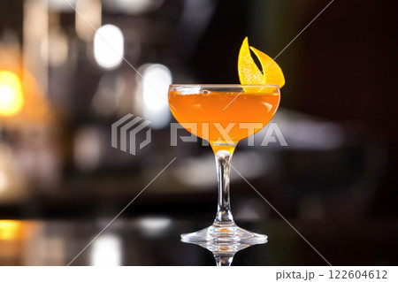 Glass of sidecar orange cocktail decorated with lemon at bar counter background. Glass of sidecar orange cocktail decorated with lemon at bar counter background. 122604612