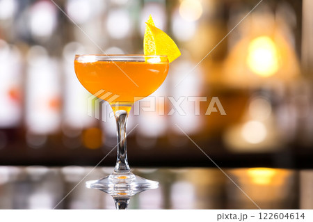 Glass of orange cocktail decorated with lemon at bar counter background. 122604614