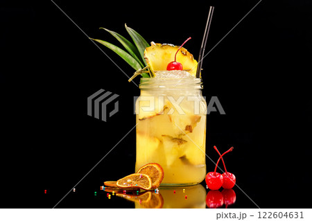 Fresh pineapple cocktail in jar decorated with cherry and ice isolated at black background. Fresh pineapple cocktail in jar decorated with cherry and ice isolated at black background. 122604631