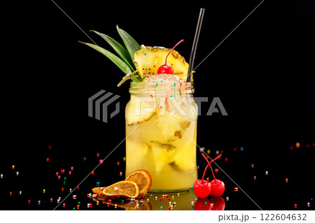 Fresh pineapple cocktail in jar decorated with cherry and colorful candies isolated at black background. Fresh pineapple cocktail in jar decorated with cherry and colorful candies isolated at black background. 122604632