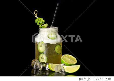 Closeup image of jar with cucumber cocktail decorated with lime isolated at black background. 122604636