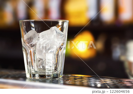 Closeup image of glass with ice cubes at bright bar counter background. 122604656