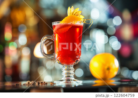 Closeup glass of red cocktail decorated with orange and apple slices at bright bar counter background. Closeup glass of red cocktail decorated with orange and apple slices at bright bar counter background. 122604759