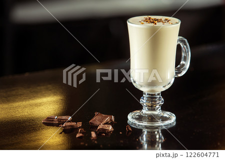 Glass of milk cocktail decorated with chocolate at table background. Glass of milk cocktail decorated with chocolate at table background. 122604771
