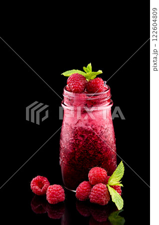 Closeup jar of fresh raspberry smoothie decorated with mint isolated at black background. 122604809