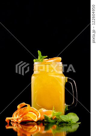 Closeup jar of fresh orange juice decorated with mint isolated at black background. Closeup jar of fresh orange juice decorated with mint isolated at black background. 122604950
