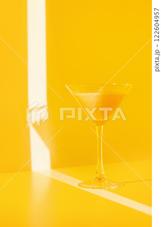 Closeup glass of banana cocktail at yellow minimal background with light stripes. 122604957